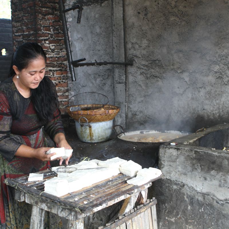 A woman fries tofu using plastic waste as a fuel 