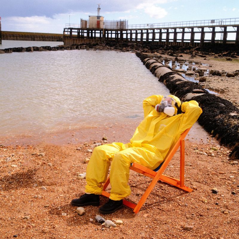 Person in hazmat suit sitting on a deckchair