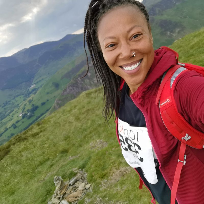 A photo of a happy young woman hiking with a beautiful landscape in the background