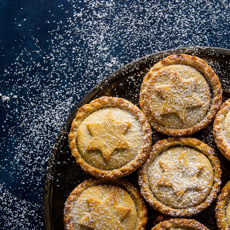 Enjoy Christmas plastic free: homemade mince pies with star-designed tops on a plate, dusted with icing sugar