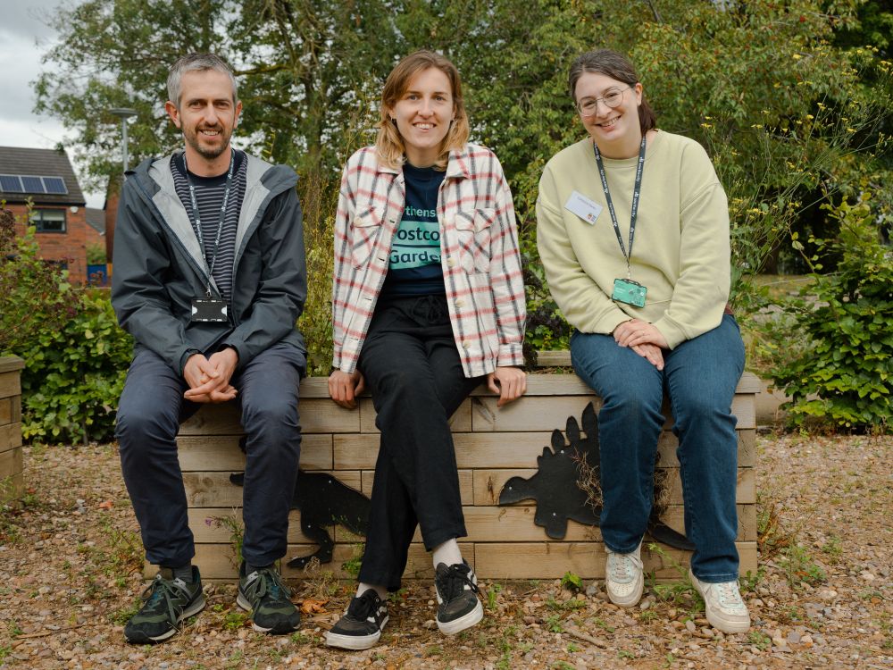 A man and two women sit on a bench smiling for the camera