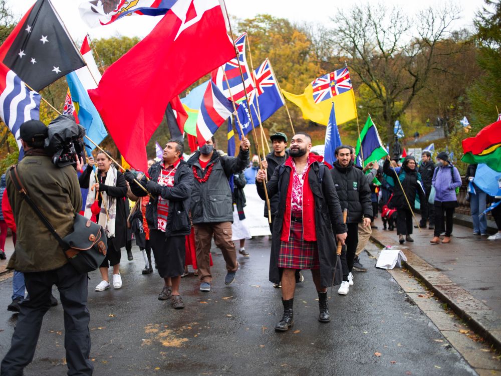 Group of international activists at a COP26 march, waving their countries' flags