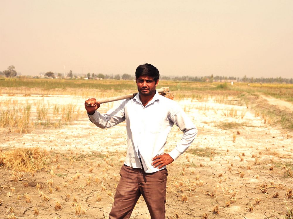 Farmer standing in drought farmland