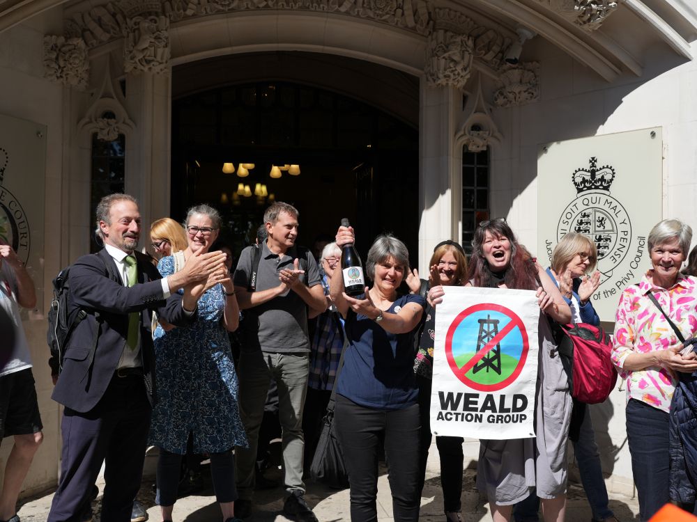 Campaigner Sarah Finch and members of Weald Action Group (holding up its group banner) celebrating a court win, outside of court, with champagne and cheers