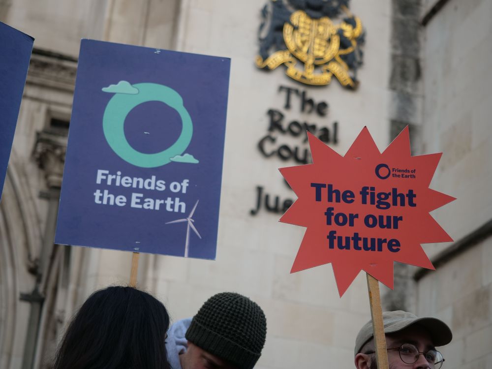 Two placards in front of the Royal Courts of Justice, one that says Friends of the Earth, the other that says "The fight for our future"