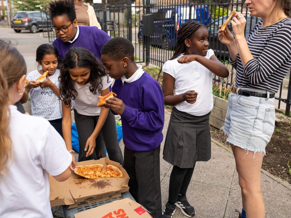 A group of school kids enjoying takeaway pizza outdoors