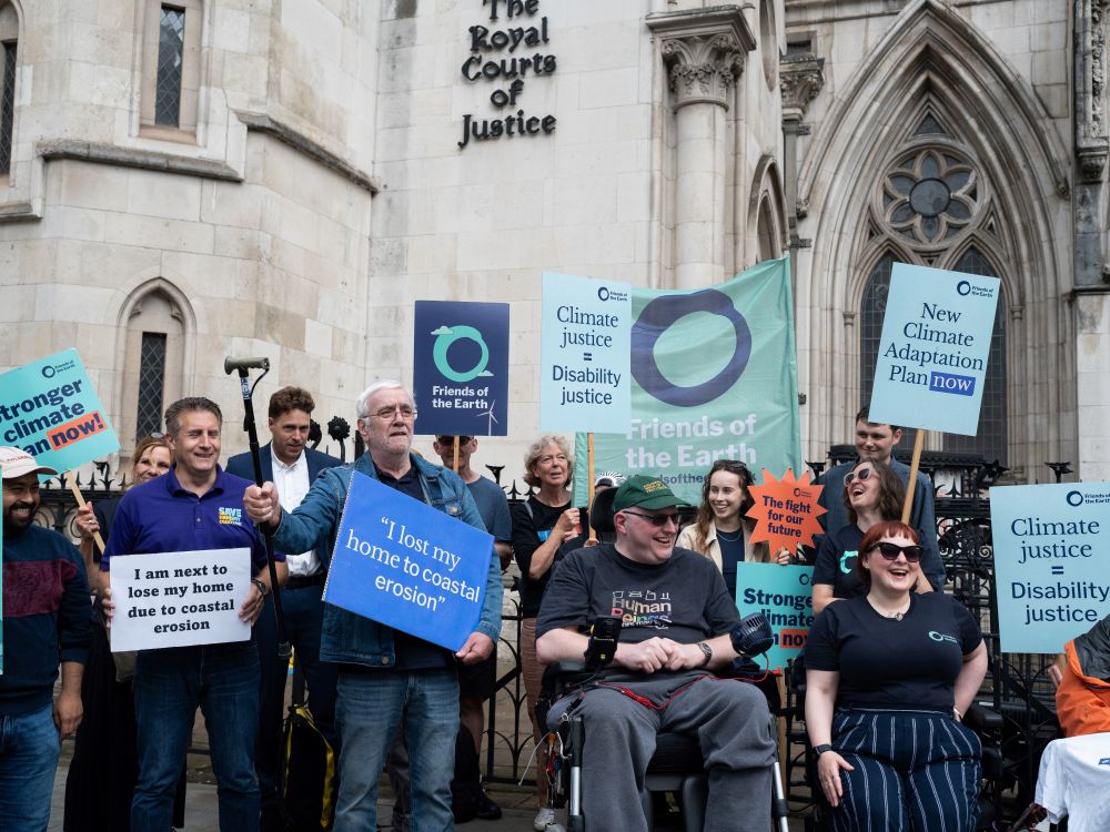 Group of people stood outside the Royal Courts of Justice holding placards