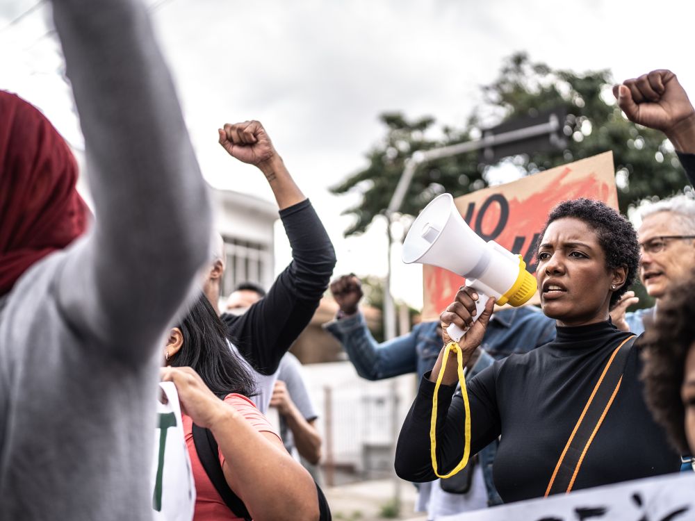 People protesting with signs, a megaphone and raised fists