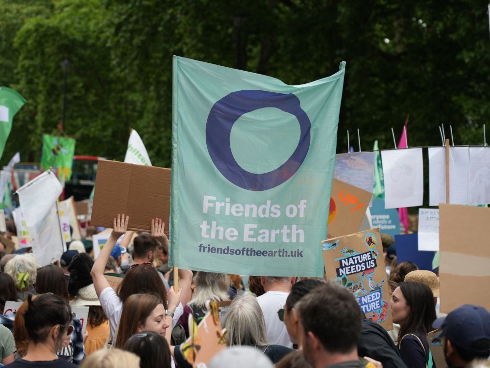 People line the streets in London. Green Friends of the Earth flag held in the middle