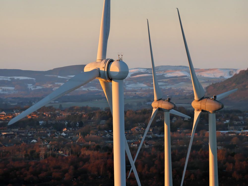 Three wind turbines overlooking a town in Scotland