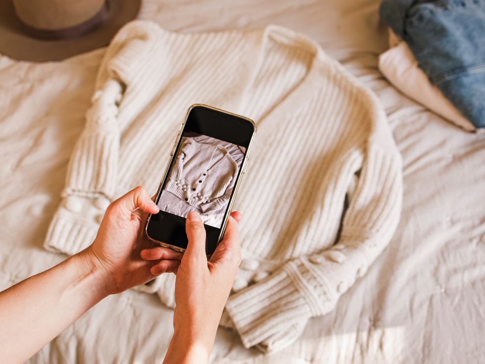 Someone taking a photo of a cardigan on their phone