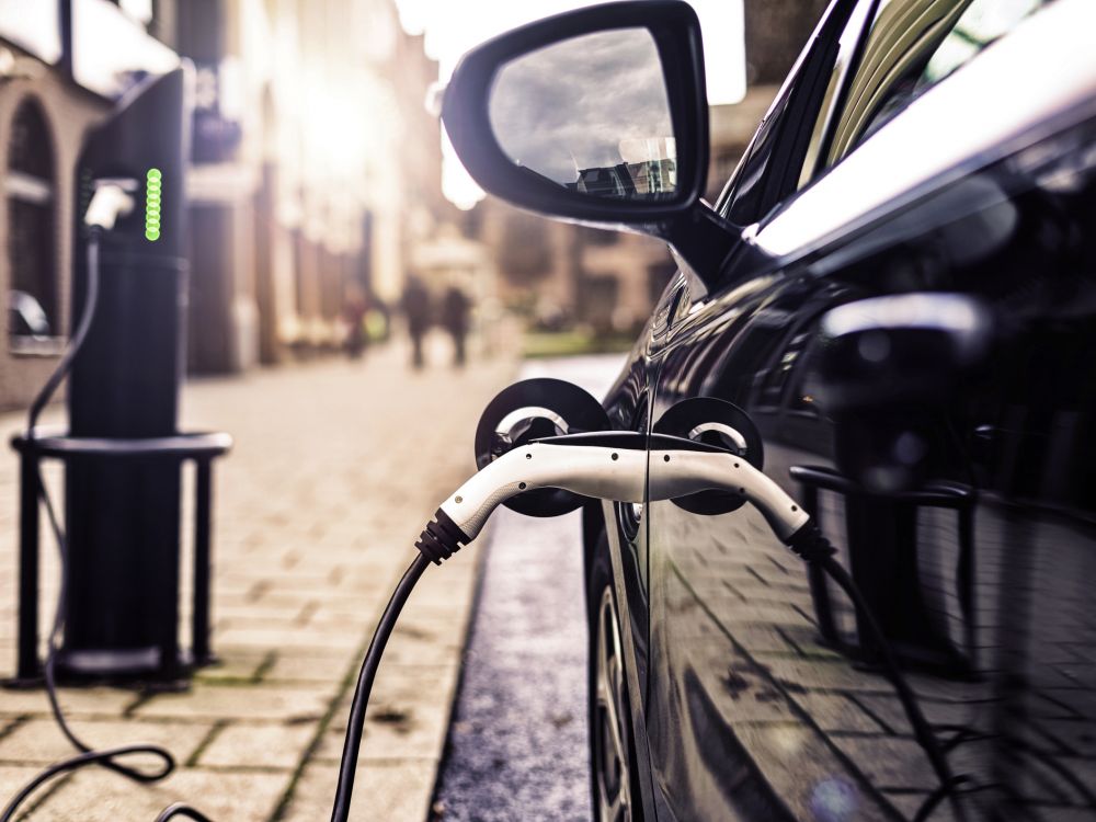 Black electric car charging at street charging point