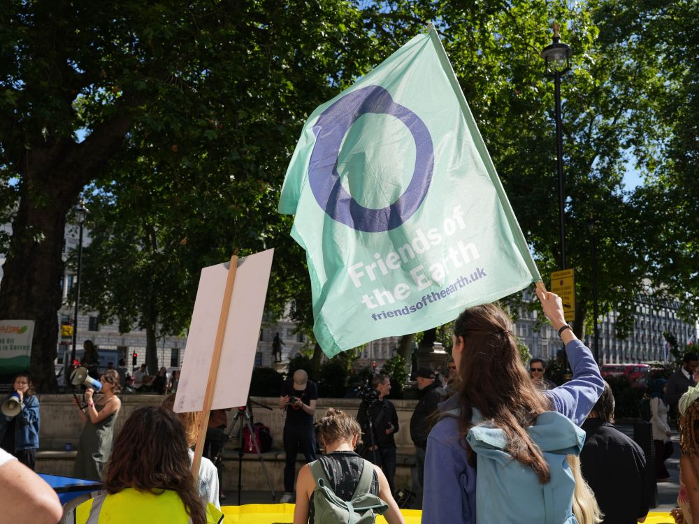 A demonstration taking place outside and a large Friends of the Earth flag is waving in the wind