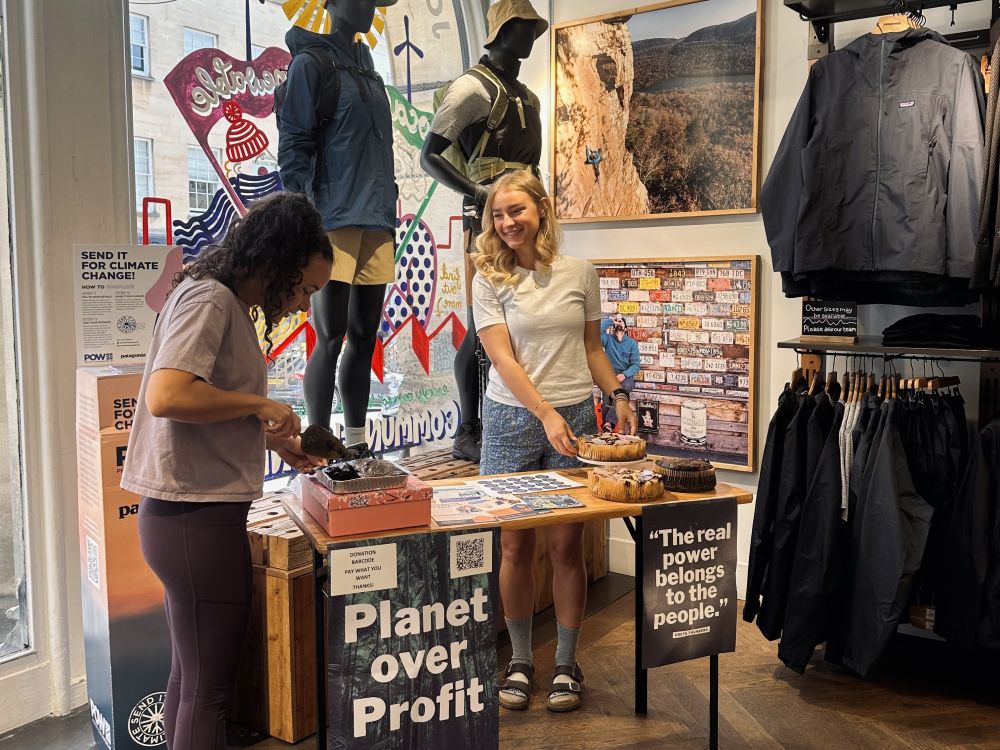 2 people happily working together on a "Planet over Profit" stall in a clothing store