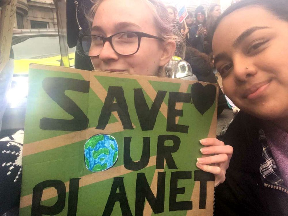 Ummi with her friend holding up a banner that reads "Save our planet" at the Youth Climate Strike in London, March 2019.